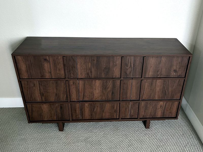 Assembled walnut dresser against a bedroom wall